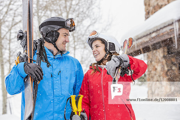 Lächelndes kaukasisches Paar mit Skiern