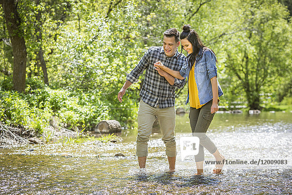 Couple holding hands wading in river