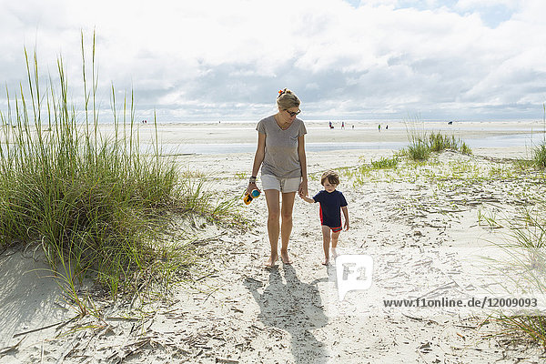 Kaukasische Mutter und Sohn gehen am Strand spazieren