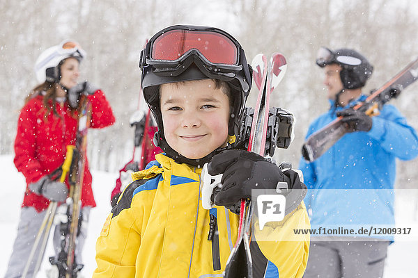 Porträt eines lächelnden kaukasischen Jungen mit Skiern