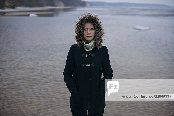 Kaukasische Frau mit Mantel in der Nähe des Meeres