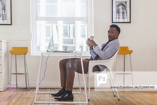 Serious Black businessman posing at computer desk