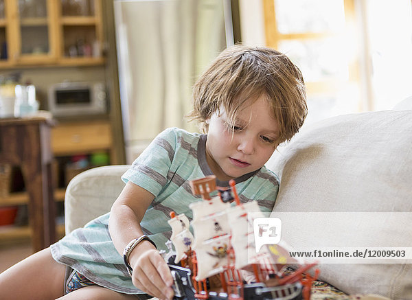 Caucasian boy sitting on sofa playing with toy boat