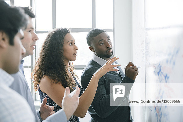 Businessman writing on whiteboard in meeting