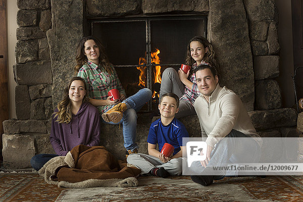 Lächelnde kaukasische Familie sitzt am Kamin