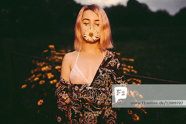 Kaukasische Frau posiert mit Blume im Mund