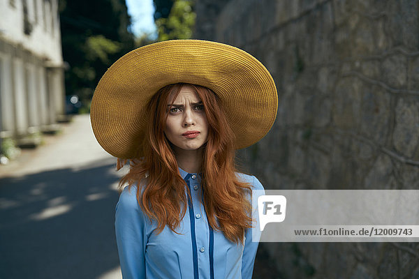 Frustrierte kaukasische Frau mit Hut in der Nähe einer Steinmauer