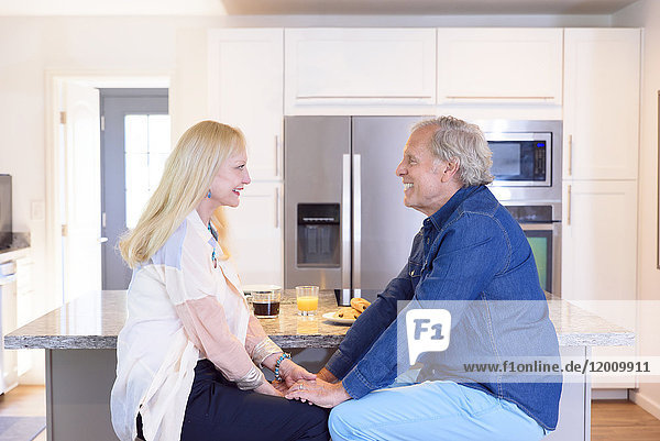 Caucasian couple holding hands in kitchen