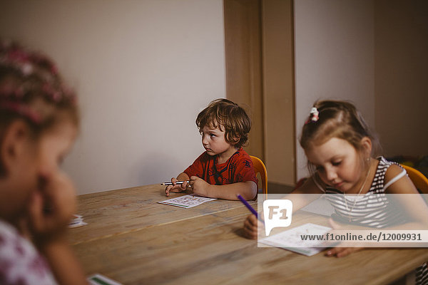 Caucasian boy and girl sitting at table coloring