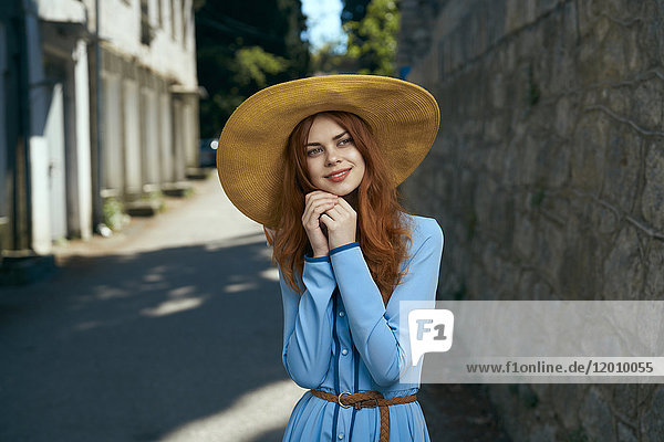 Pensive Caucasian woman wearing hat near stone wall