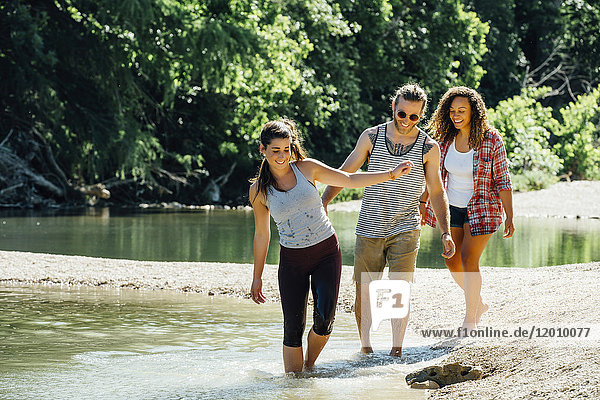 Smiling friends wading in river