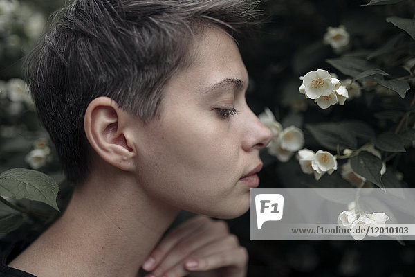 Profile of Caucasian woman smelling flowers