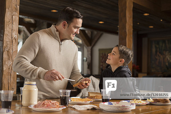 Caucasian father making sandwich for son at table