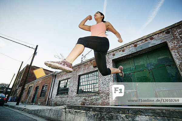 Mixed race woman jumping off loading dock