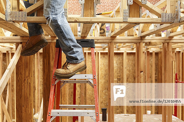 Legs of black man on ladder at construction site