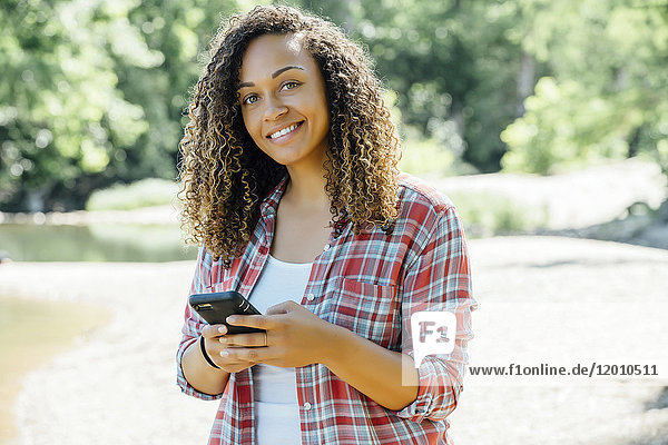 Smiling mixed race woman texting on cell phone outdoors