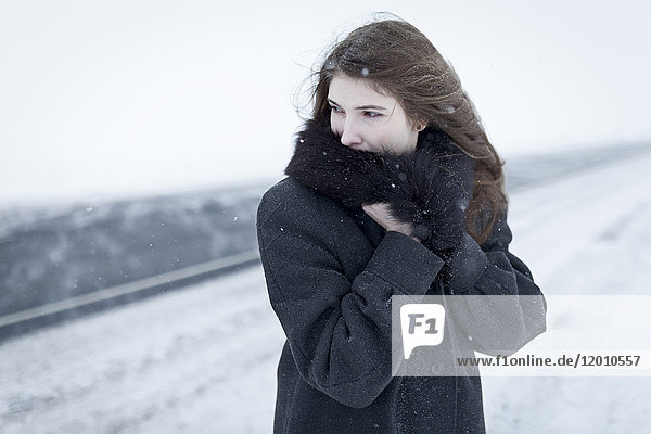 Caucasian woman nestling in fur collar outdoors in winter
