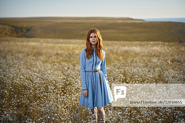 Kaukasische Frau steht in einem Feld mit Wildblumen