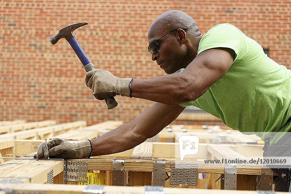 Black man hammering nail at construction site