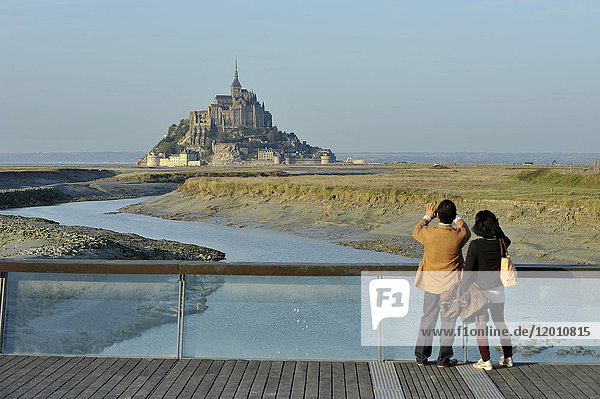 France  Lower Normandy Region  Manche Department  Mont St-Michel seen from the dam on Couesnon river  couple of Asian visitors taking a picture.