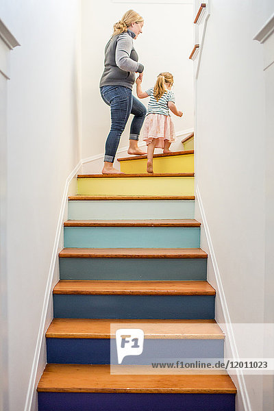 Kaukasische Mutter und Tochter klettern mehrfarbige Treppe