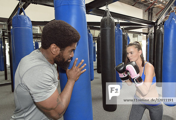 Man training woman using punching bag