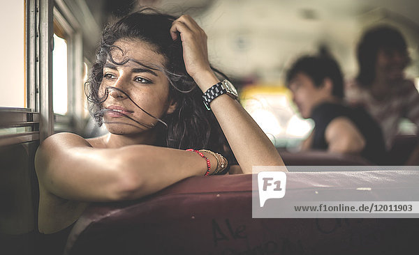 Eine junge Frau sitzt in einem Schulbus und schaut aus dem Fenster.
