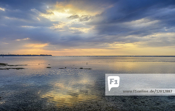 Sonnenuntergang über dem Ozean und Licht- und Wolkenformationen  die sich im seichten Wasser auf der Insel Gili (Indonesien) spiegeln.