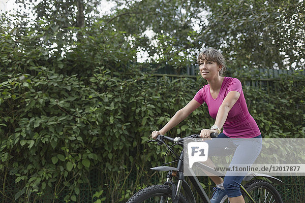 Full length of woman riding bicycle by plants