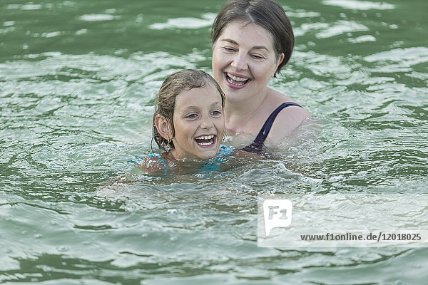 Cheerful grandmother and granddaughter swimming in pool