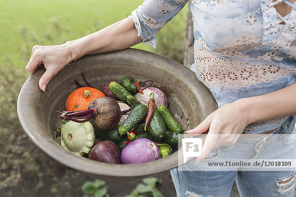Midsection of woman holding vegetables in container