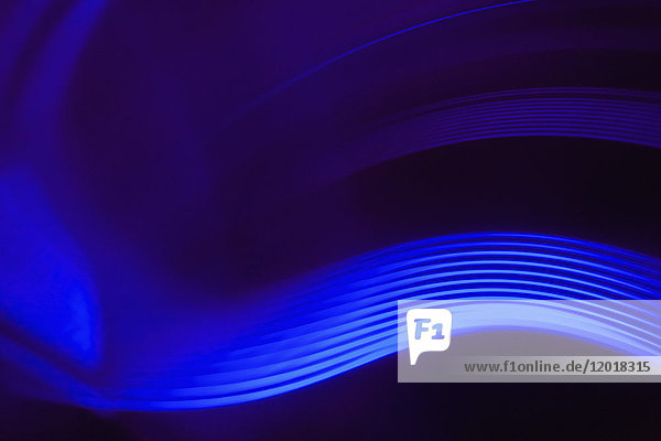 Abstrakte Nahaufnahme von leuchtend blauen Lichtspuren vor schwarzem Hintergrund