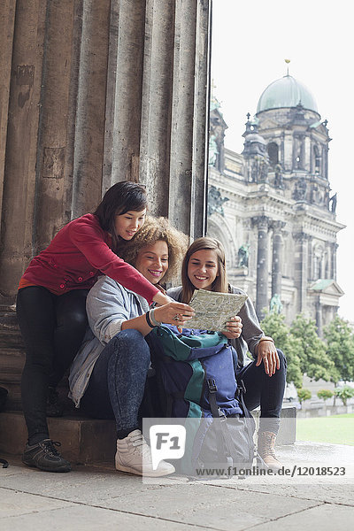 Young female tourists reading map at Altes Museum against Berlin Cathedral  Germany