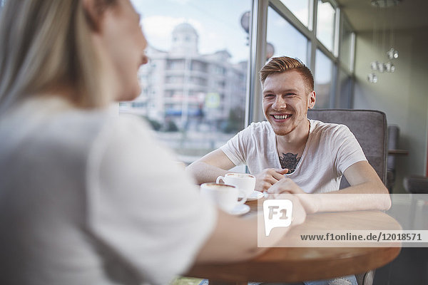 Smiling man sitting with girlfriend at restaurant