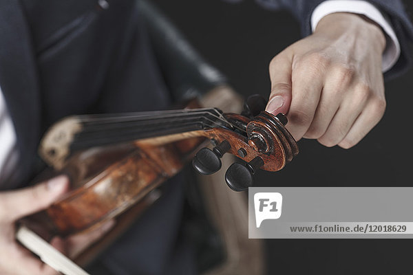 Abgeschnittenes Bild eines Musikers beim Stimmen von Geigensaiten