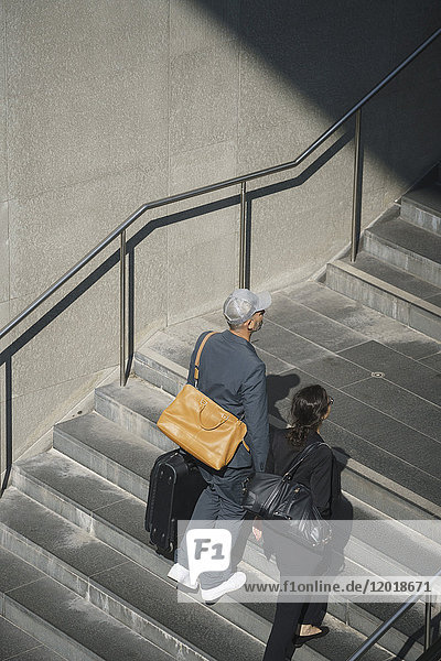Full length of business colleagues walking with bag on steps