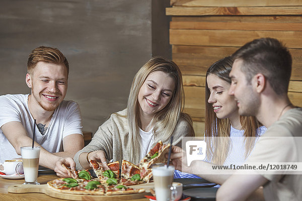 Young friends enjoying pizza at restaurant
