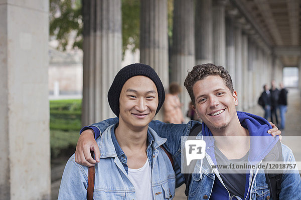 Porträt von lächelnden jungen männlichen Freunden  die mit den Armen herumstehen  Berlin  Deutschland