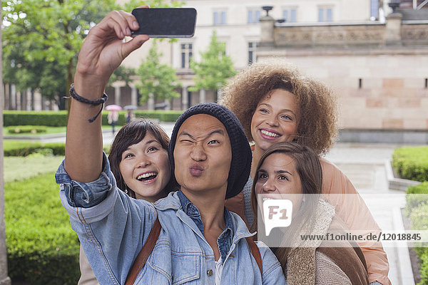 Young man making face while taking selfie with female friends  Berlin  Germany