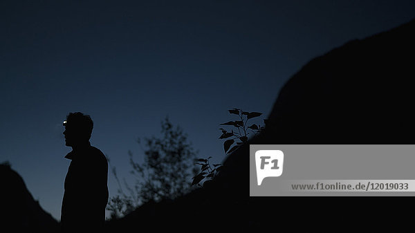 Seitenansicht des auf dem Berg stehenden Silhouettenmannes gegen den klaren Himmel