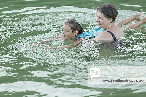 Grandmother teaching granddaughter in swimming pool