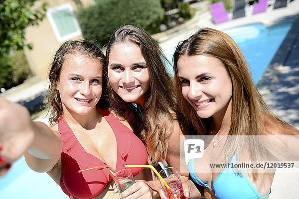 Drei schöne junge Frau  die selfie zusammen durch den poolside von Resort Schwimmbad während Urlaub sonnigen Sommertag.