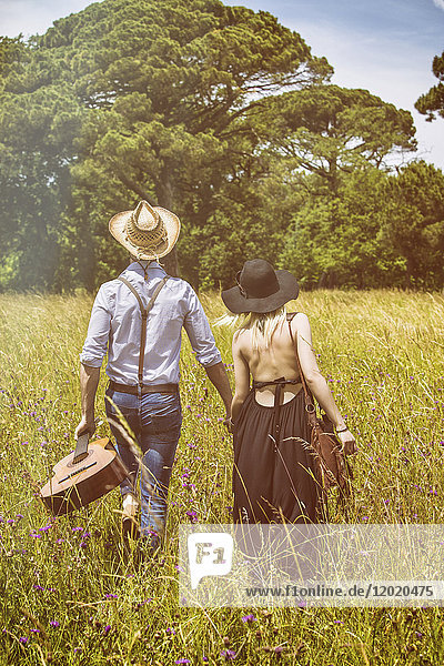 Young couple Hipster ride in the country  holding in one hand a guitar the other
