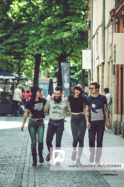 Gruppe junger Hipster  die eine Straße entlanggehen  städtische Umgebung