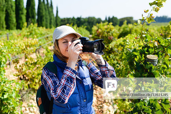 Fröhliche junge Frau beim Wandern und Fotografieren mit ihrer Spiegelreflexkamera - Cepage Grenache  Chateauneuf du Pape  cotes du Rhone  Frankreich