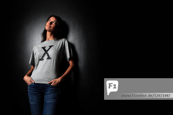 Braune Frau im Atelier mit einem T-Shirt mit einem X. Konzeptuelles Bild zum Thema ''Born under X''.