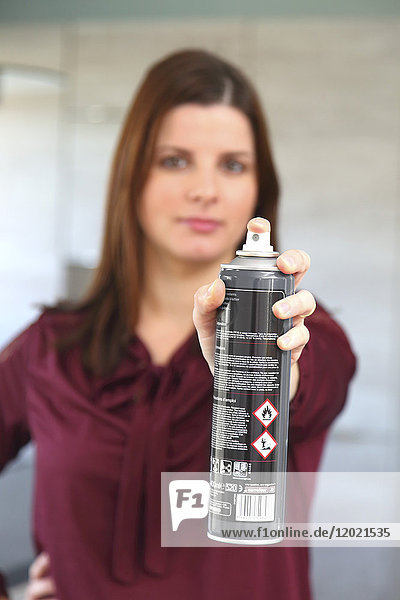 Junge Frau zu Hause mit Luftspray
