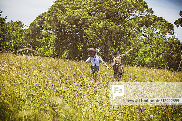 Junges Paar Hipster reiten auf dem Land  halten die Hand über in einem Feld
