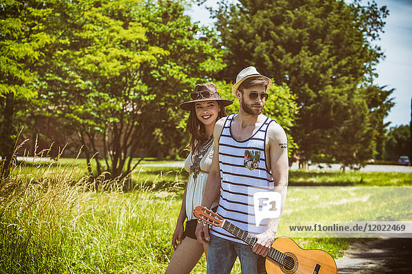 Porträt eines jungen Paares Hipsterfahrt auf dem Lande  eine Gitarre in der Hand