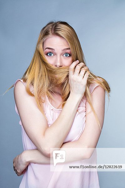 Porträt einer jungen staunenden Frau  Haare vor dem Mund